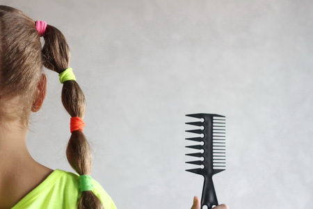 Hairstyle and hairdo. Haircare concept. Hair extensions and natural hair. Accessories and tools for hairstyles. Girl holding scissors or comb. Long hair, braid.の写真素材