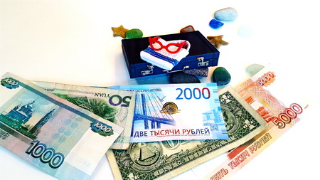 The money for the trip is under the suitcase. Banknotes of different countries. Dollar, ruble, yuan.の写真素材