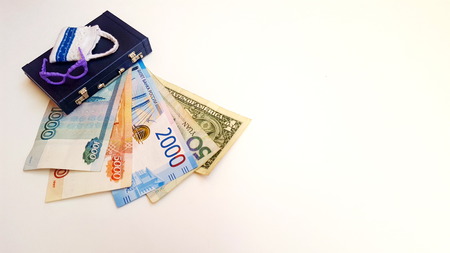 The money for the trip is under the suitcase. Banknotes of different countries. Dollar, ruble, yuan.の写真素材