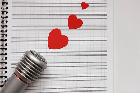 Microphone and paper red hearts are located on a clean music notebook. The concept of music and love. Valentines dayの写真素材