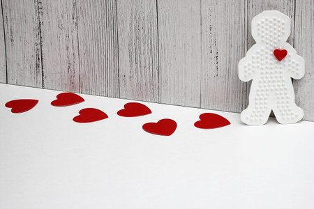 Red cardboard hearts are on a white background. Plastic figure of a man with a red heart. concept of...