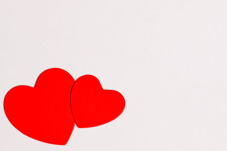 Valentines Day. Two red cardboard hearts are arranged together on a white background. Concept of...
