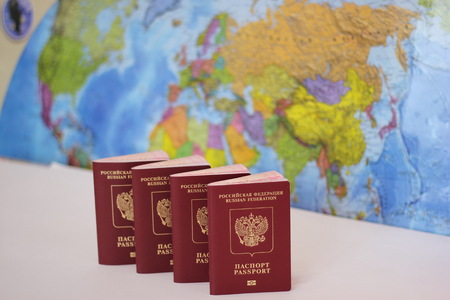 Biometric russian passports are in a row on the background of the world map. . The passport of the Russian Federation. The concept of tourism and travel.の写真素材