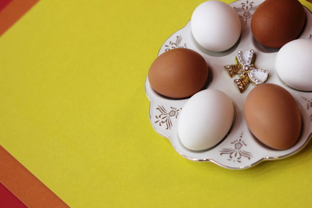 White and brown eggs lie on a special plate on a yellow background. Preparation for Easter. Diet and Healthy eating.の写真素材