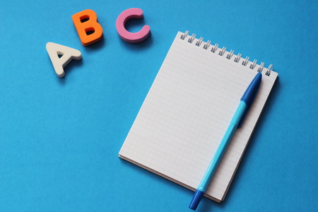 ABC-the first letters of the English alphabet on a blue background. Notebook and pen. Empty space for text. Learn foreign languages. English for beginnersの写真素材