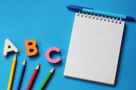 ABC-the first letters of the English alphabet on a blue background. Notebook and pen. Pencils of different colors and small globe. Empty space for text. Learn foreign languages. English for beginnersの写真素材