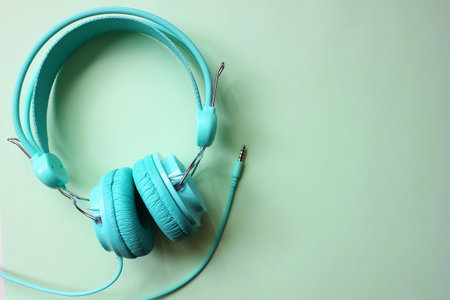 Headphones turquoise on a light green background. Audio devices. Copy Space.