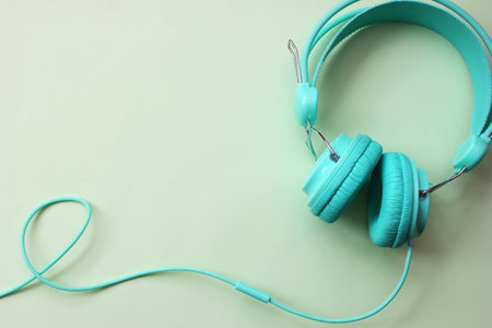Headphones turquoise on a light green background. Audio devices. Copy Space.