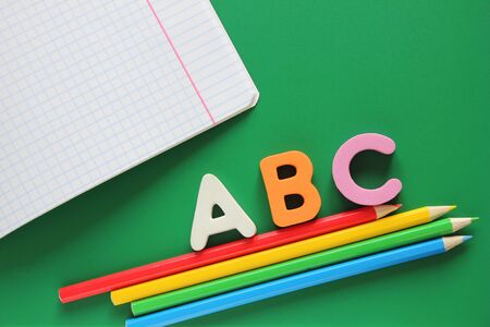 ABC-the first letters of the English alphabet on a green background. school notebook and colored pencils. Empty space for text. Empty space for text. Learn foreign languages. English for beginnersの写真素材