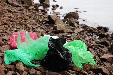 A bunch of reusable, multi-colored plastic bags polluting the environment. Garbage on the seashore....