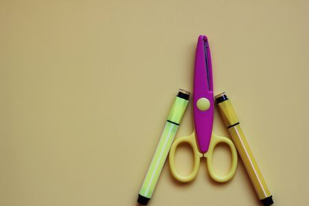 Two Yellow markers and the scissors located on a yellow background. School Stationery.の写真素材