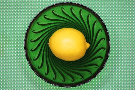 Fresh yellow lemon on a green plate on a green backgroundの写真素材