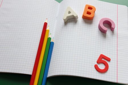 ABC-the first letters of the English alphabet and pencils of different colors on the school notebook. Empty space for text. Learn foreign languages. English for beginnersの写真素材