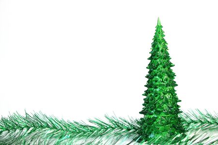 Green toy Christmas tree and tinsel are isolated on white background. Symbol of The new year. Copy space.の写真素材