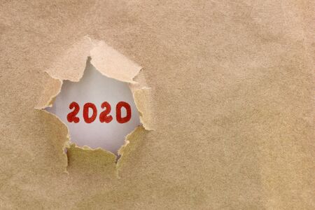 Ripped or torn brown paper revealing new year 2020 on white background. Happy New Year. Copy space.の写真素材