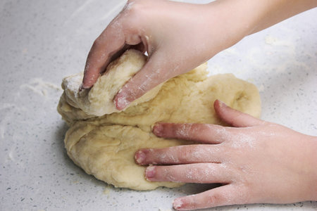 Children's hands knead a piece of dough. The process of kneading the doughの写真素材
