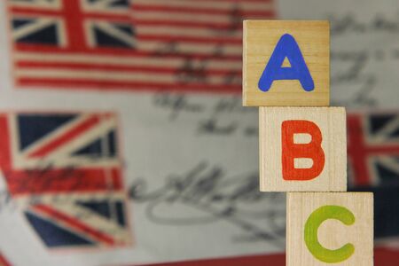 ABC-letters of the English alphabet on wooden cubes on the background of images of the English flag. Learning foreign language. English for beginners.の写真素材