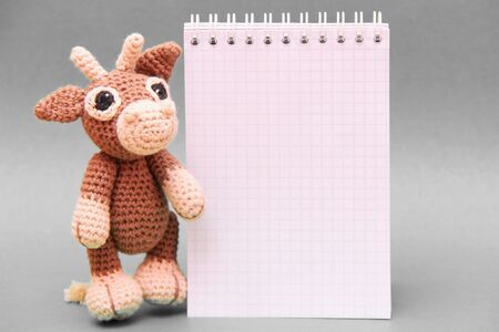 The bull is the symbol of the New year 2021. A knitted brown toy bull next to a Notepad . Copy Space.の写真素材