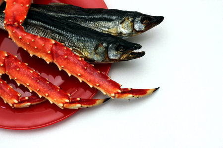 Cooked Kamchatka crab and dried salted fish on a red plate. Beer snack. Seafood.