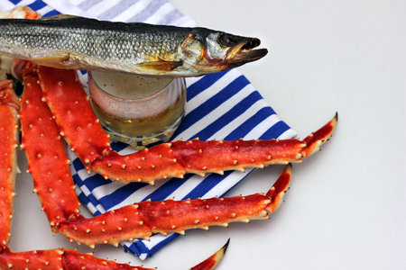Beer in a glass and an appetizer to beer. Cooked crab and salted dried fish. Striped vest. Striped...