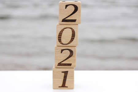 Wooden blocks with the numbers 2021 stand on top of each other like a pyramid near the sea. Happy New year. Concept of tourism, recreation and travel.の写真素材