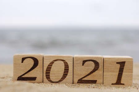Wooden blocks with the numbers 2021 are located on the sand on the beach near the sea. Happy New year. Concept of tourism, recreation and travel.の写真素材