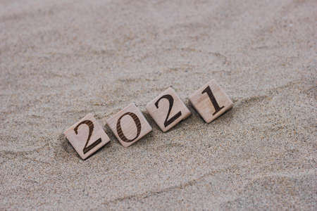 Wooden blocks with the numbers 2021 are located on the sand on the beach. Happy New year. Concept of tourism, recreation and travel.の写真素材