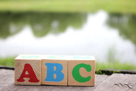 ABC -the first letters of the English alphabet on wooden toy blocks which are on the old boards in the outdoor near the lake . Learning foreign language.の写真素材