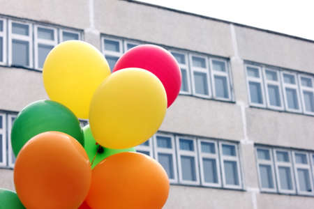 Colored balloons on the background of the grey school building. Back to school concept.の写真素材