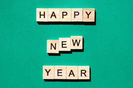 Happy New Year - an inscription made in black letters on wooden blocks . Green background. Holiday conceptの写真素材