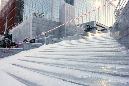 the stairs are covered In ice. Stairs after an icy rain. Ice-slick steps. Protective tape near the slippery ice stairs. Winter has come. cleaning of city stairs from ice and snow.の写真素材