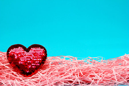 Red sparkling heart with sequins on a blue and pink background. Valentine's Day concept. The idea of...