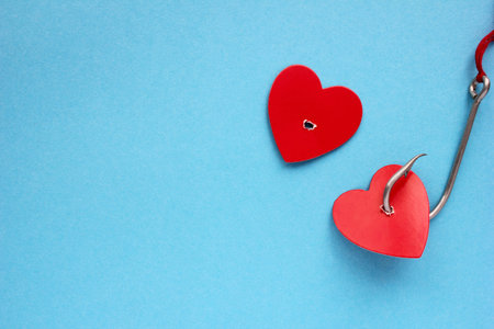 Red heart on a hook on a blue background. The concept of love. Valentines day.