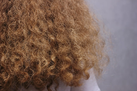 natural curls, curly hair. Beautiful, strong, healthy female hair. A girl with thick natural, long wavy hair standing with her back to the camera.の写真素材