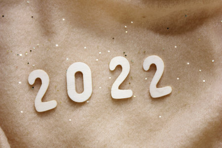New Years Eve 2022. New Years number is lined with wooden numbers on a beige fleece blanket...