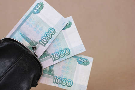 Retro black wallet and three banknotes with a face value of 1000 rubles sticking out of it.の写真素材