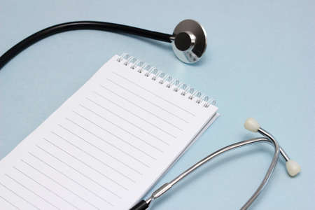 The doctor's workplace. A stethoscope and a notebook for writing with a clean page. Medicine and health concept.の写真素材