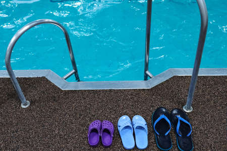 Swimming pool. Three pairs of rubber slippers standing next to each other - mens, womens and childrens. Family subscription to the pool.の写真素材