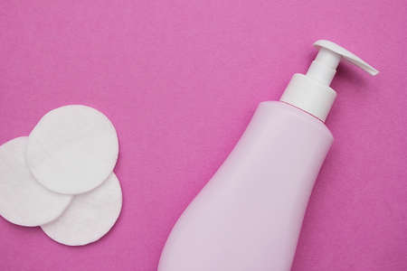 Hygiene. Cleansing the face. Cosmetic products for skin care. Pink bottle, cotton pads on a pink background.の写真素材