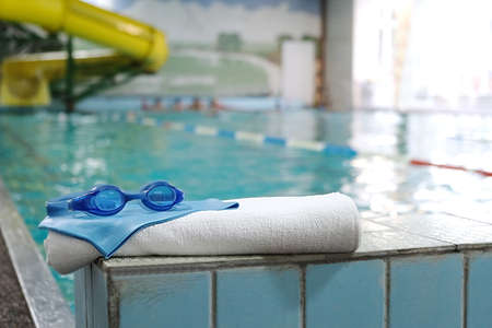 swimming pool. accessory for the pool - a towel, a rubber cap and swimming goggles on the background of the swimming track.の写真素材