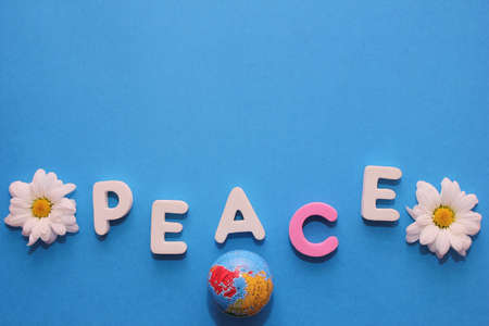 Word PEACE made by letters near little figure of a globe and a flowers of white chrysanthemums. Copy space.の写真素材