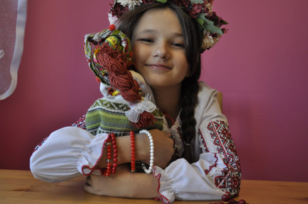 Little girl in Ukrainian national costume sitting on a wooden table and smilingの写真素材