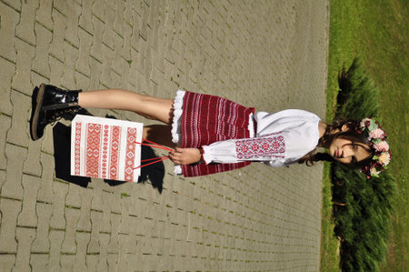 View of a beautiful girl in a traditional Romanian costume on the countryside.