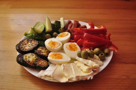 eggs with vegetables on a white plate on a wooden table.の写真素材