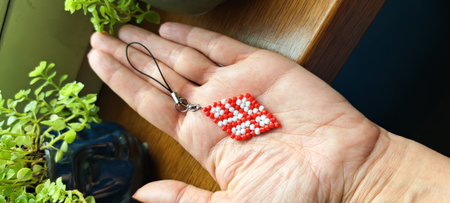 Hand with a red cross-shaped pendant on a wooden background.