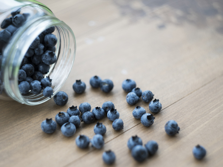 Blueberry in the glass jar at wooden backgroundの写真素材