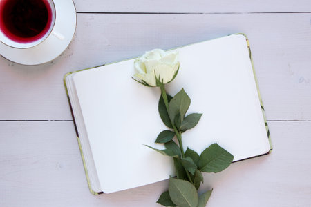 Romantic mood mock up for your text and design, top view, flat lay, album sheet with white rose and pen at rustic wooden background. Blank greeting card or illustration sheet, copy past.の写真素材