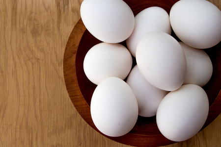 White eggs in a bowl, wooden background, closeupの写真素材