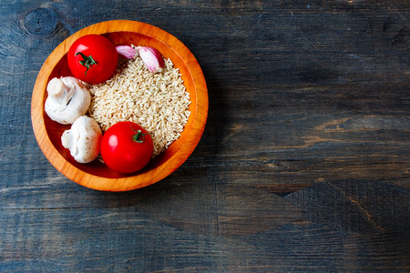 Uncooked rice in wooden bowl with ingridients on wooden background with copy space. Shallow dofの写真素材
