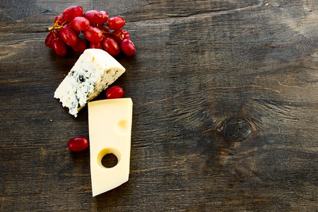 Cheese and grapes on rustic wooden background. Top view.の写真素材